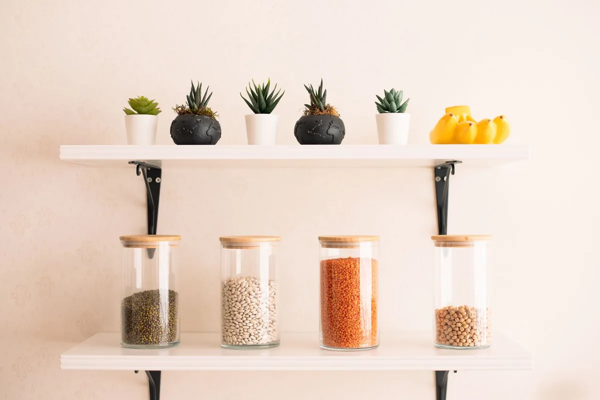 Glass jars of lentils and grains on a white wall shelf