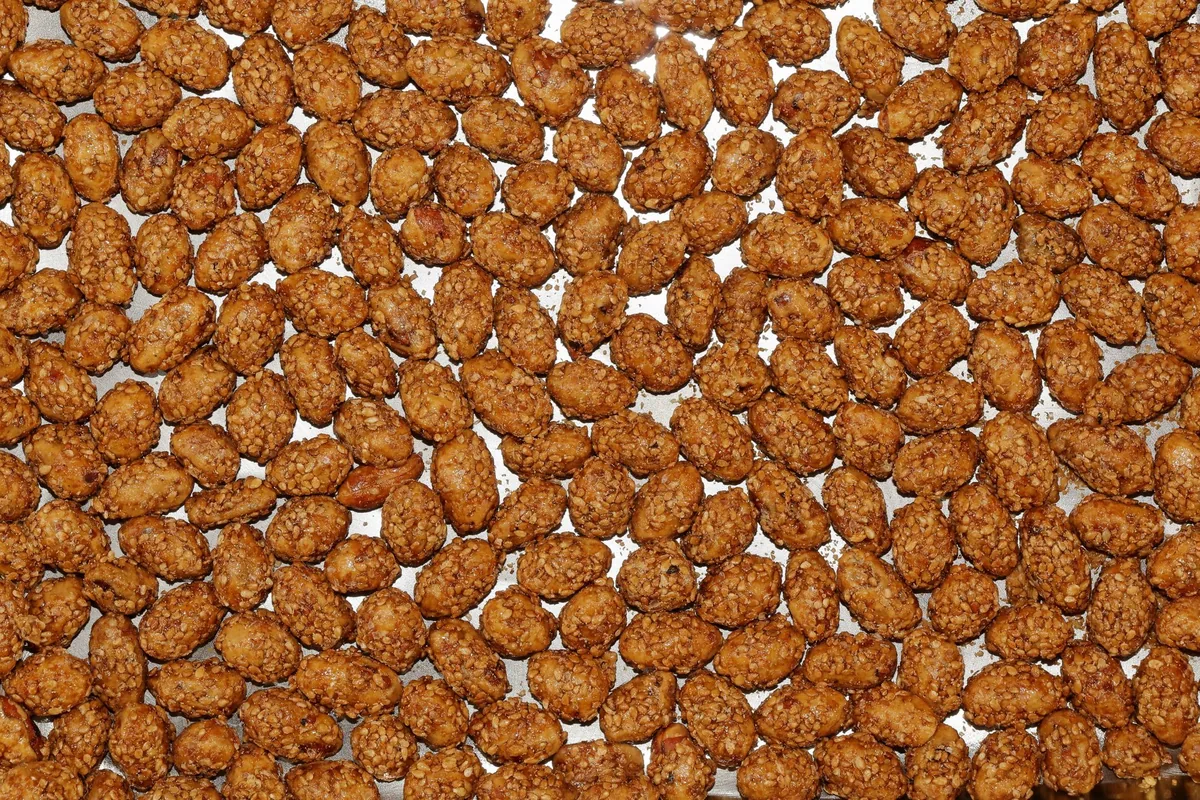 Golden roasted almonds spread in a single layer on a metal baking tray