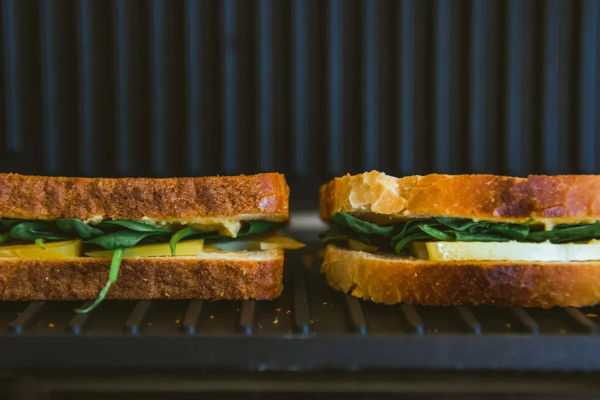 Toasted sandwiches with greens on a dark grill