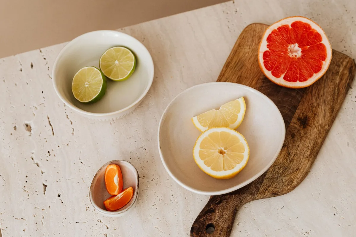 Halved oranges and lemons arranged on a pale wooden cutting board