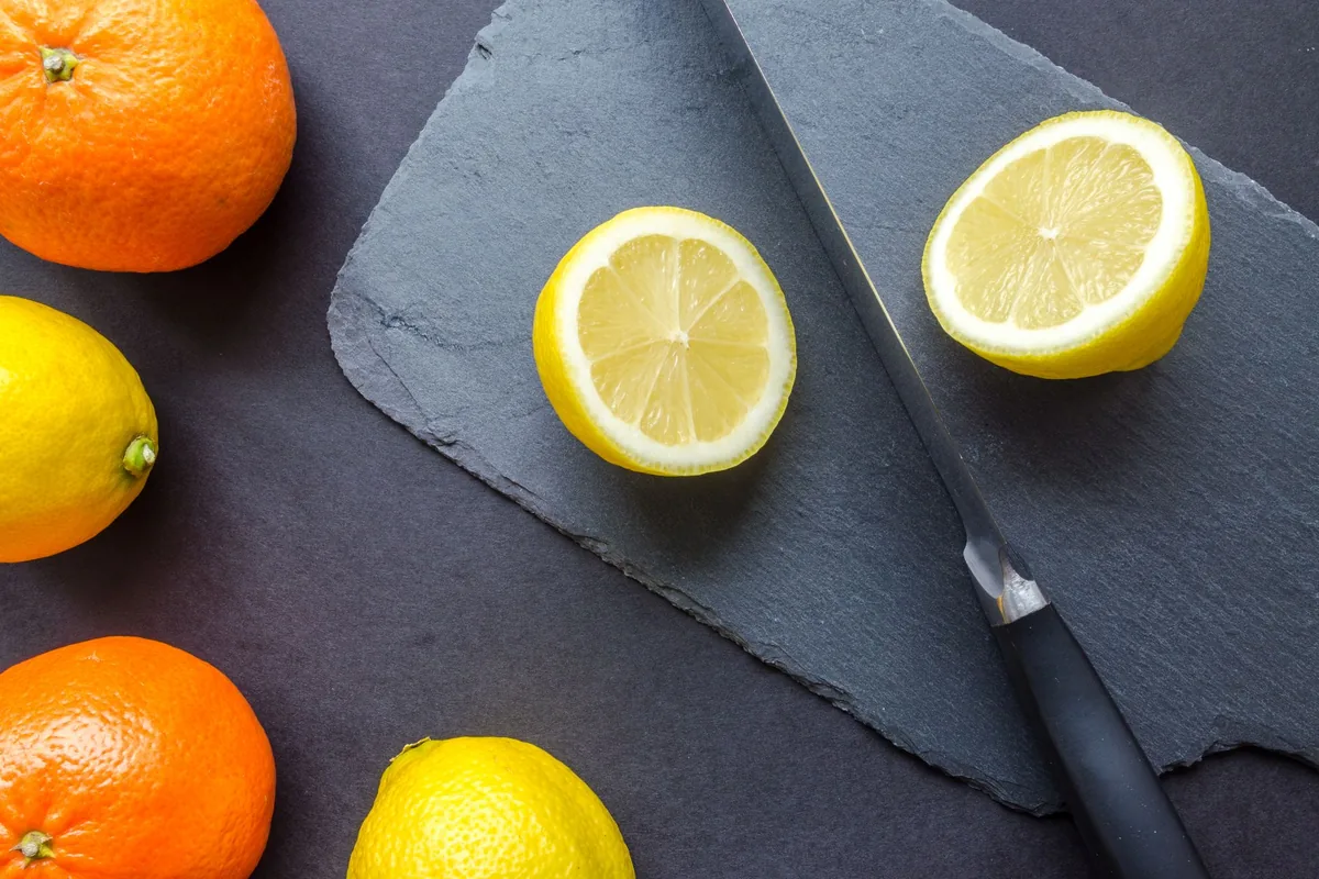 Halved oranges, lemons and limes cut side up on a wooden chopping board