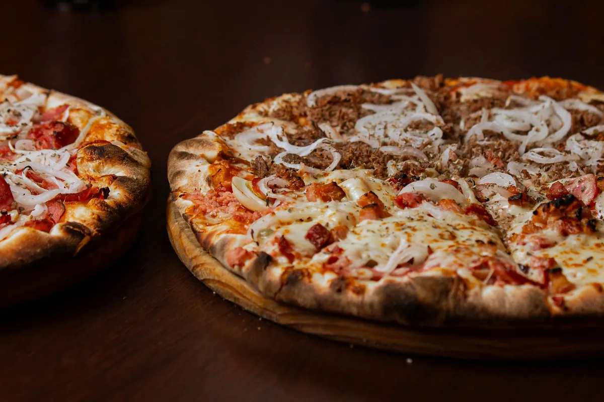 Two baked pizzas on a wooden table