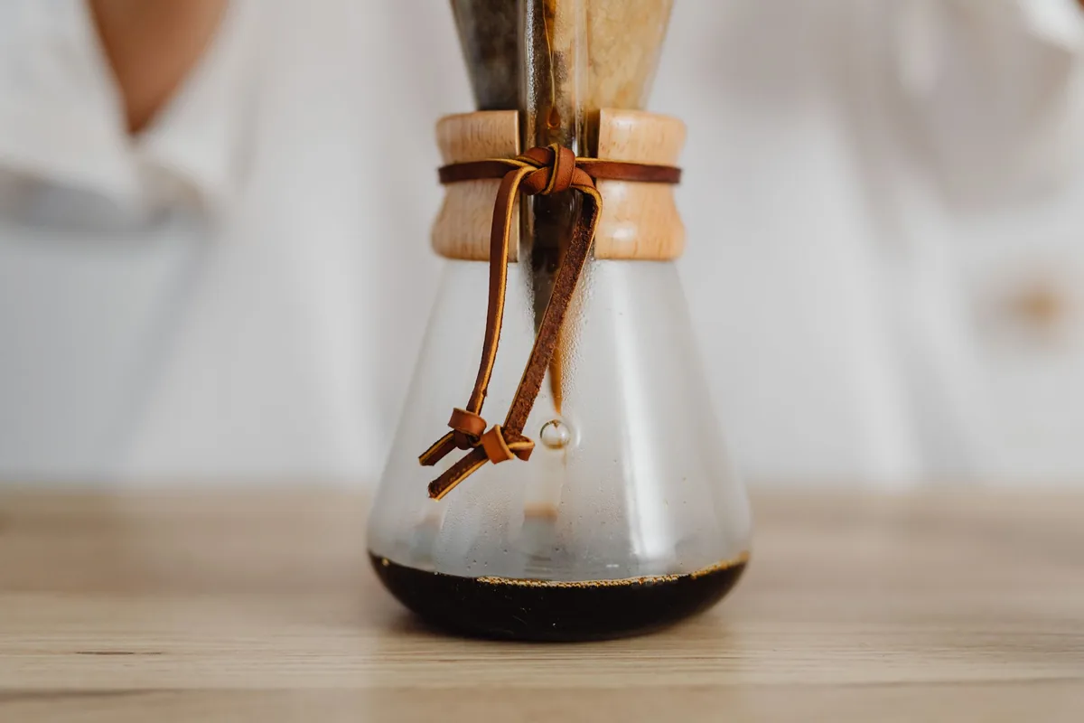 Hot coffee dripping through a paper filter into a pot below