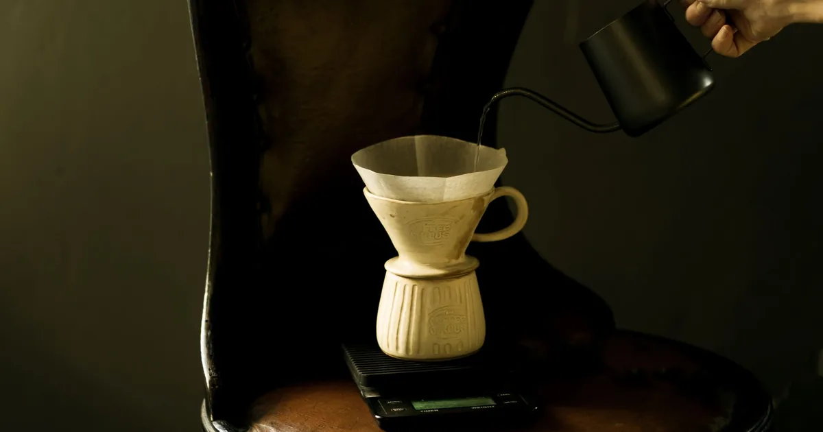 Hot water being poured from a gooseneck kettle into a pour-over coffee dripper