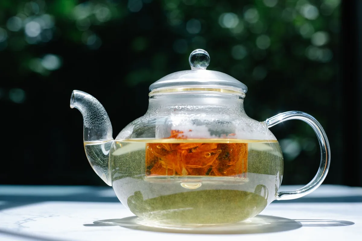 A glass teapot of herbal tea outdoors