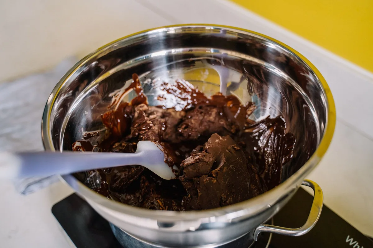 Melted chocolate in a steel bowl with a spatula