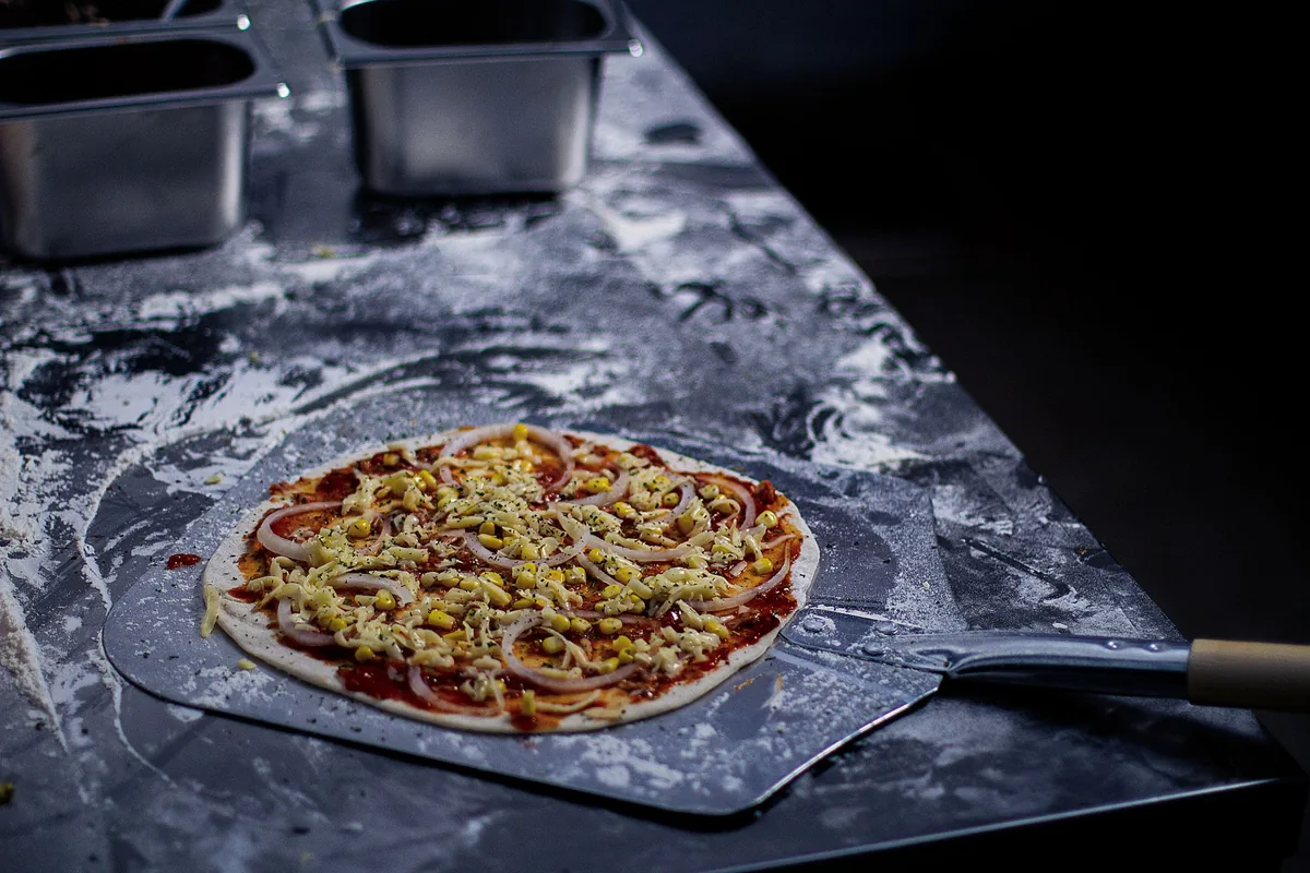 Metal pizza peel resting beside an outdoor pizza oven