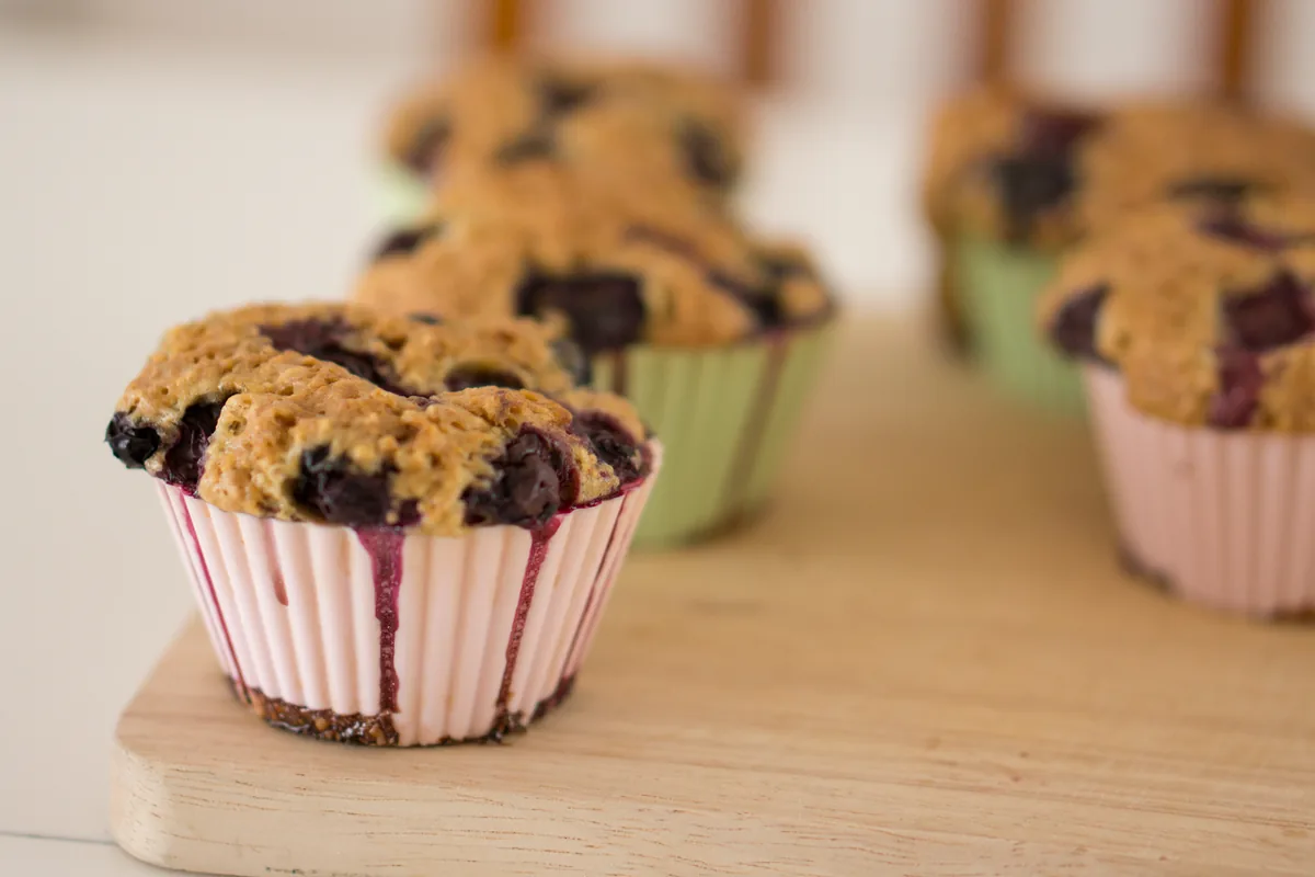 Paper cupcake liners in a muffin pan, each filled partway with pale batter