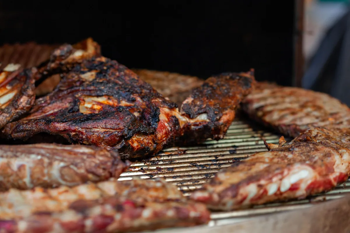 Racks of pork ribs cooking on the grate of a smoker