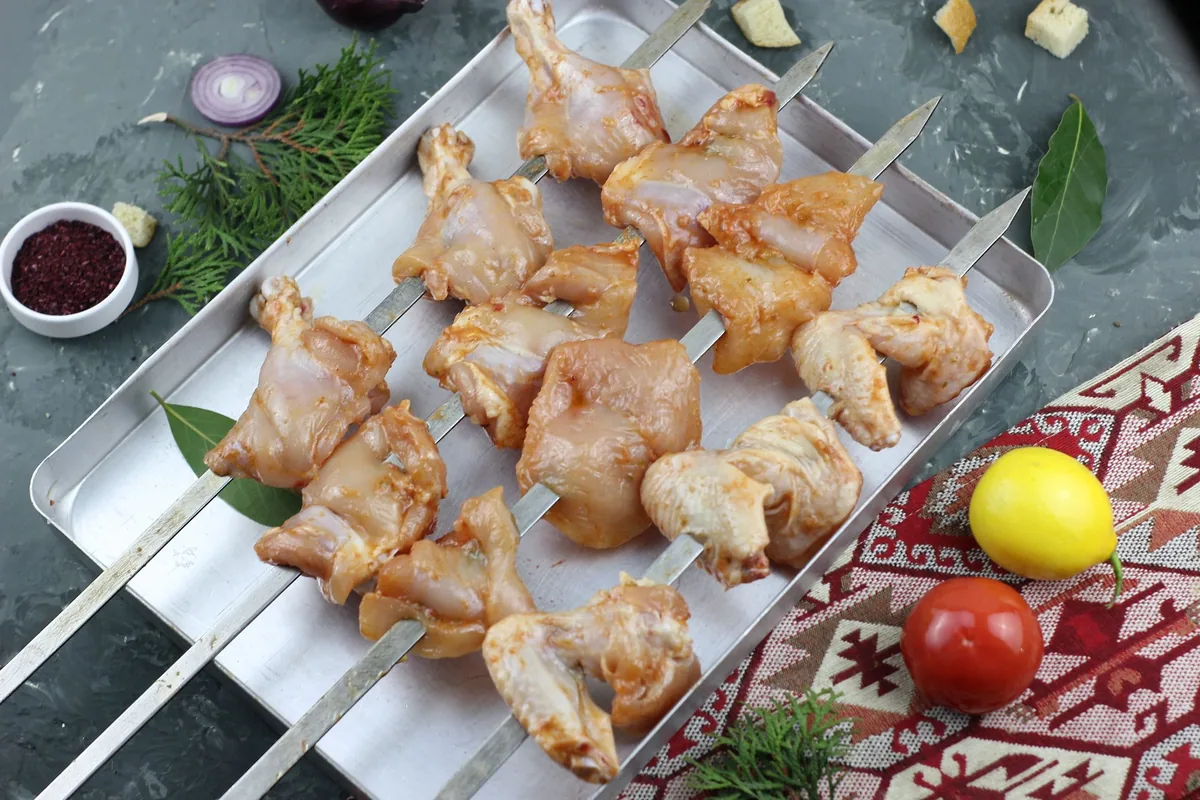 Raw chicken necks and backs arranged on a stainless steel tray