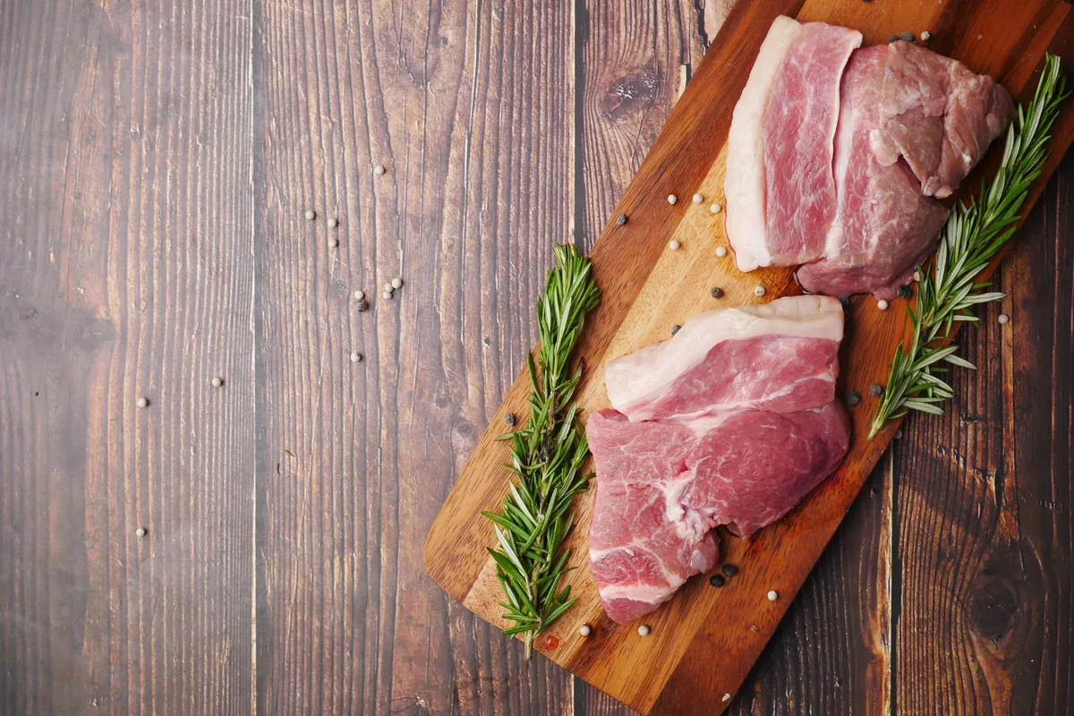 Raw pork cuts with rosemary on a rustic board