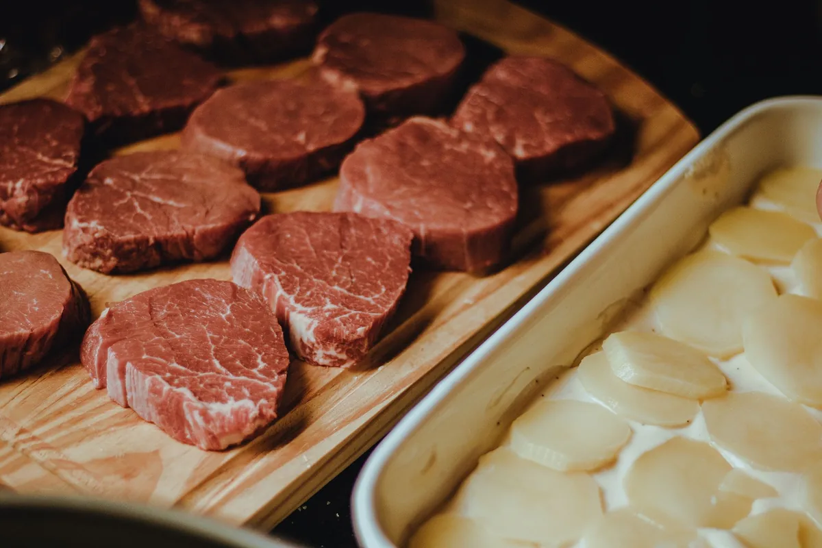 Raw steaks laid out on a wooden tray
