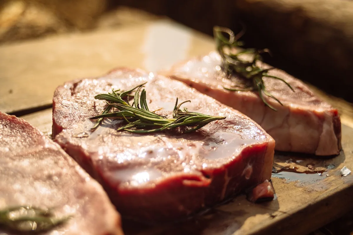 Raw steaks with rosemary on a board