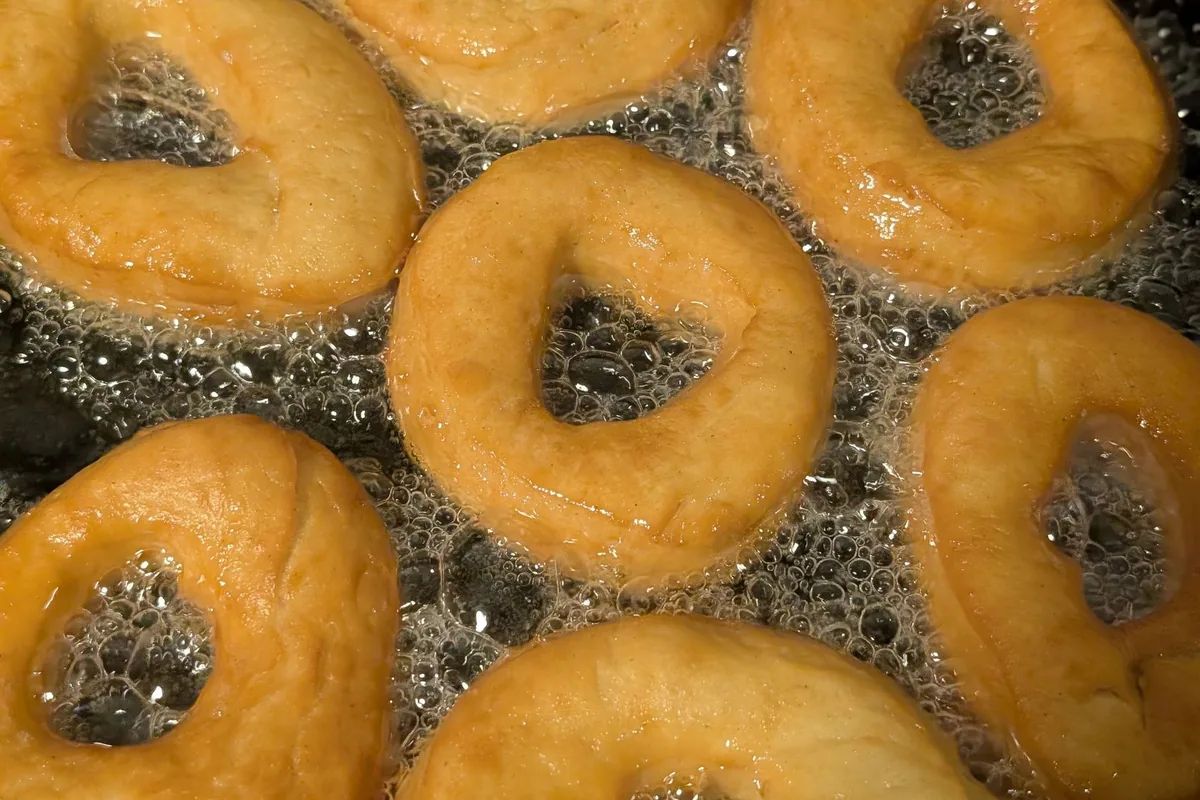 Rings of dough frying golden in a deep pot of oil