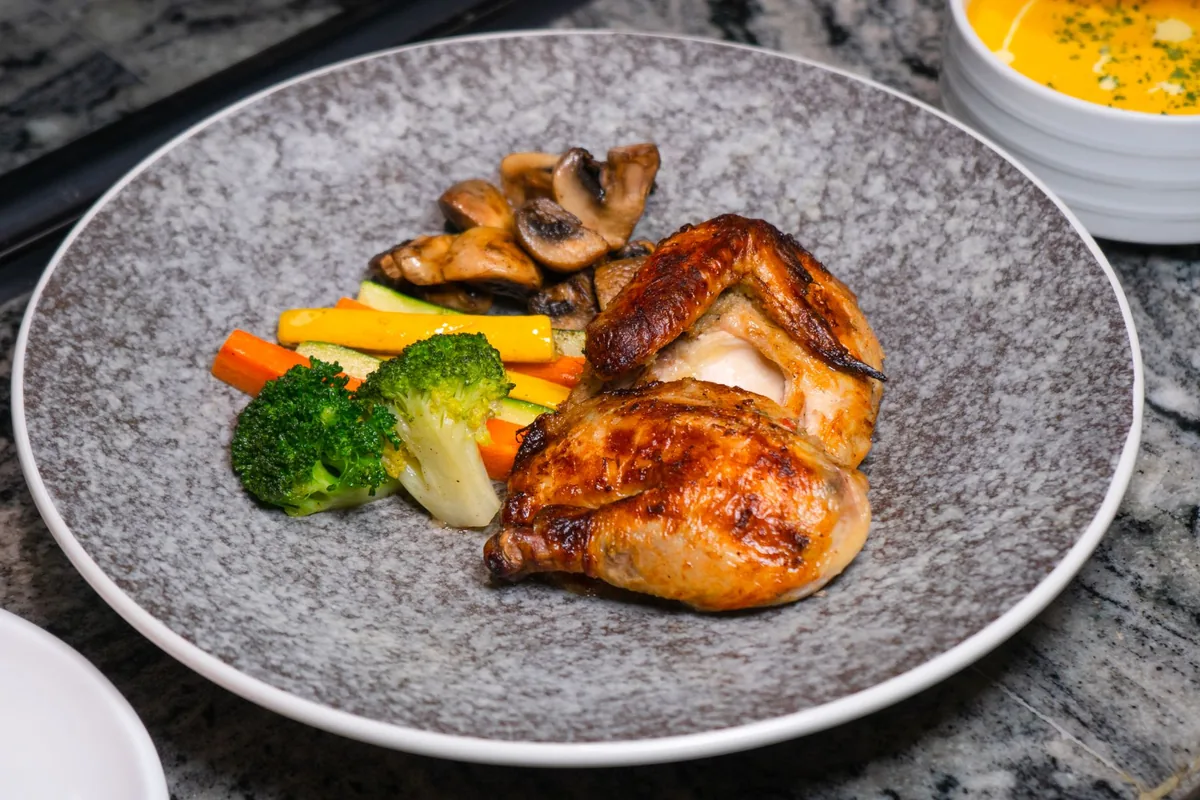 Roast chicken with vegetables on a grey plate
