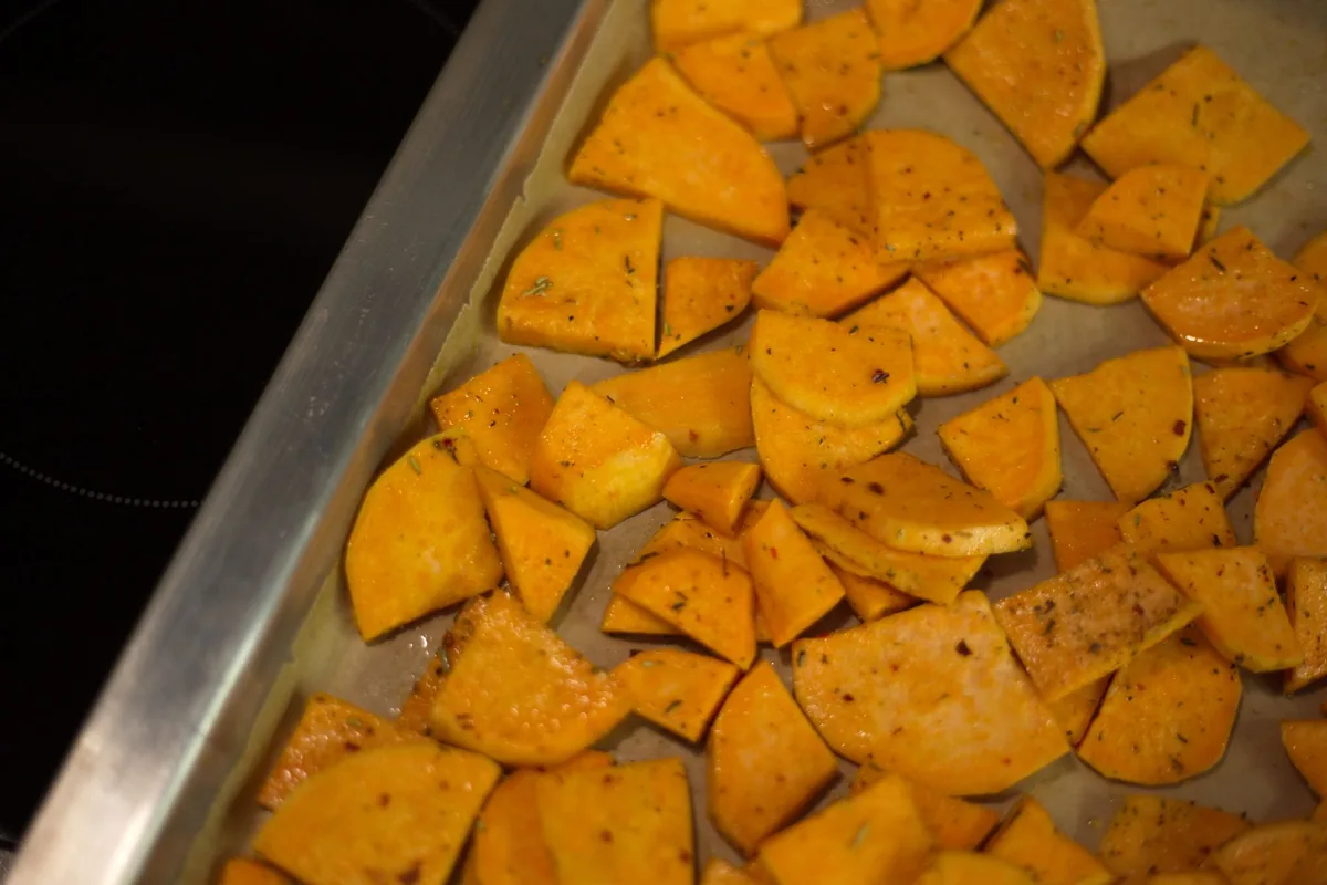 Roasted vegetables spread across a lined baking tray, edges browned