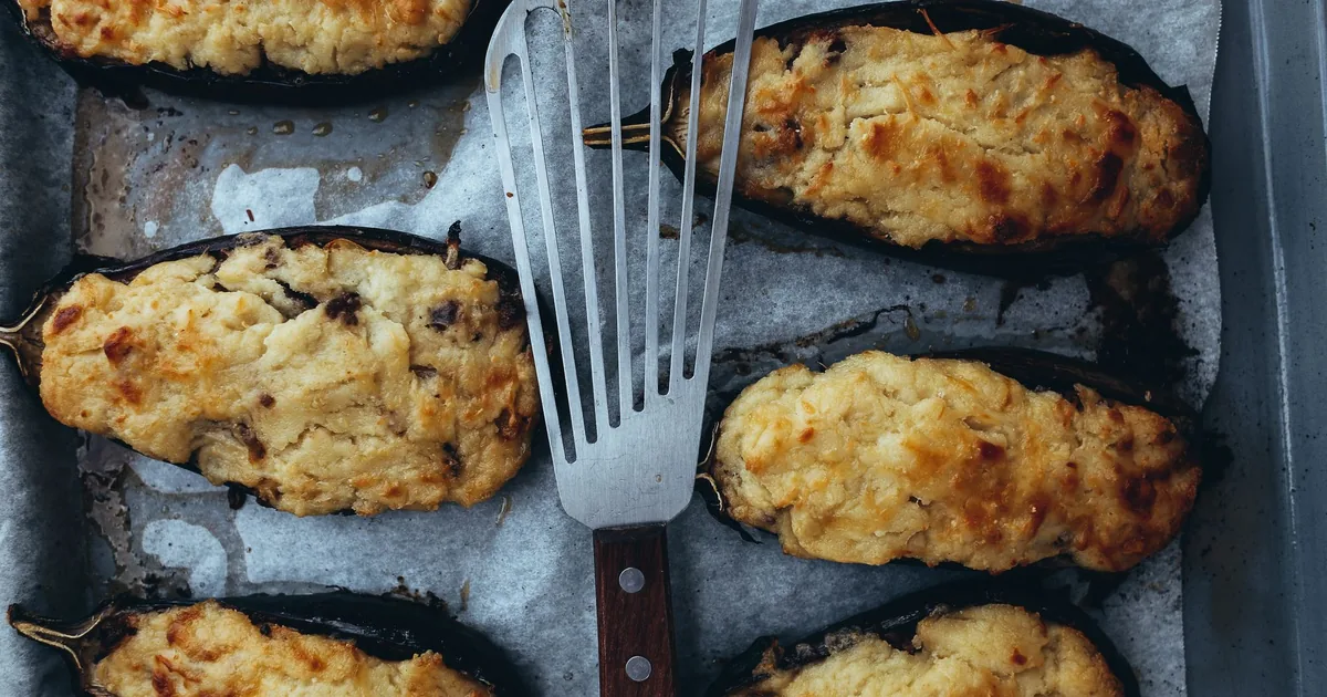 Stuffed baked eggplant halves on a lined baking tray