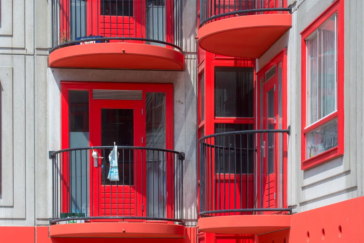 Rows of balconies on the facade of a modern apartment block under a clear blue sky