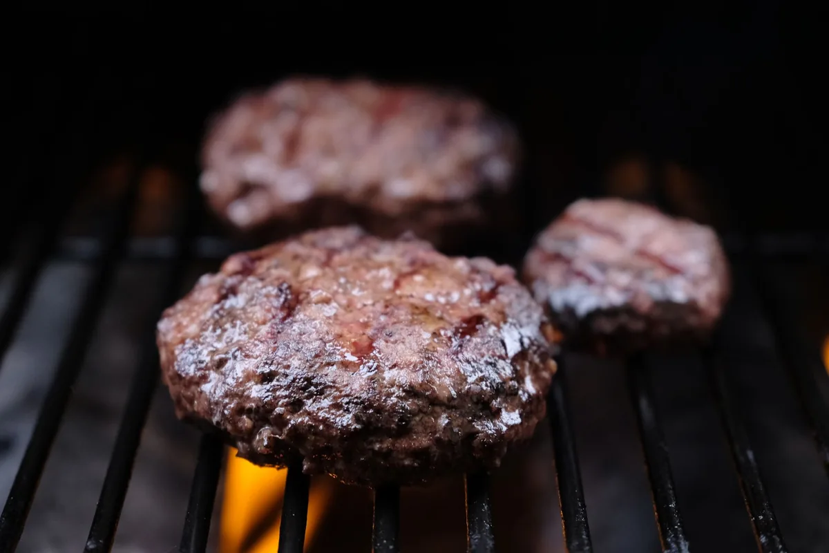 Burger patties cooking over a flame