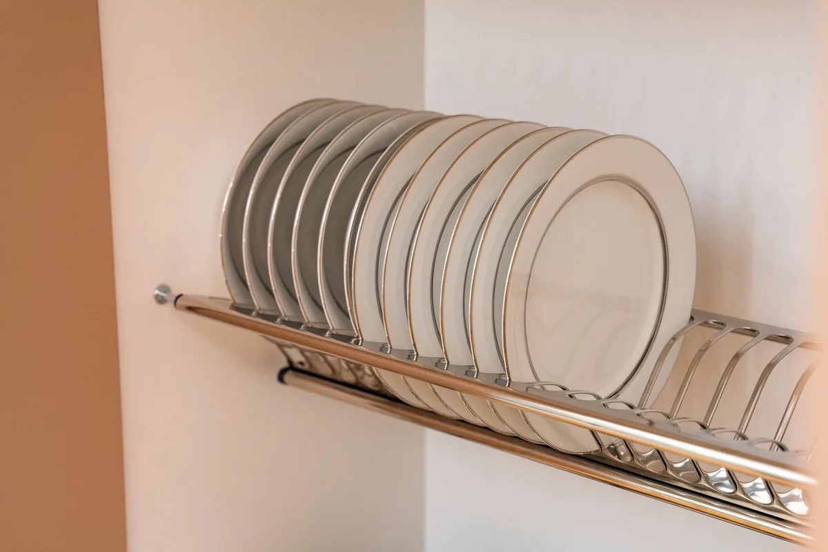 Rows of clean plates standing in the slots of a metal drying rack