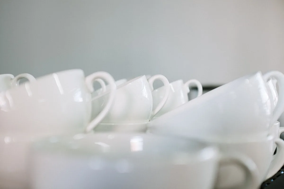 Rows of empty white coffee cups lined up on a long table