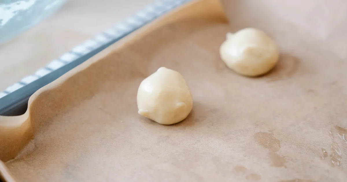 Rows of evenly sized cookie dough balls spaced out on a lined baking sheet