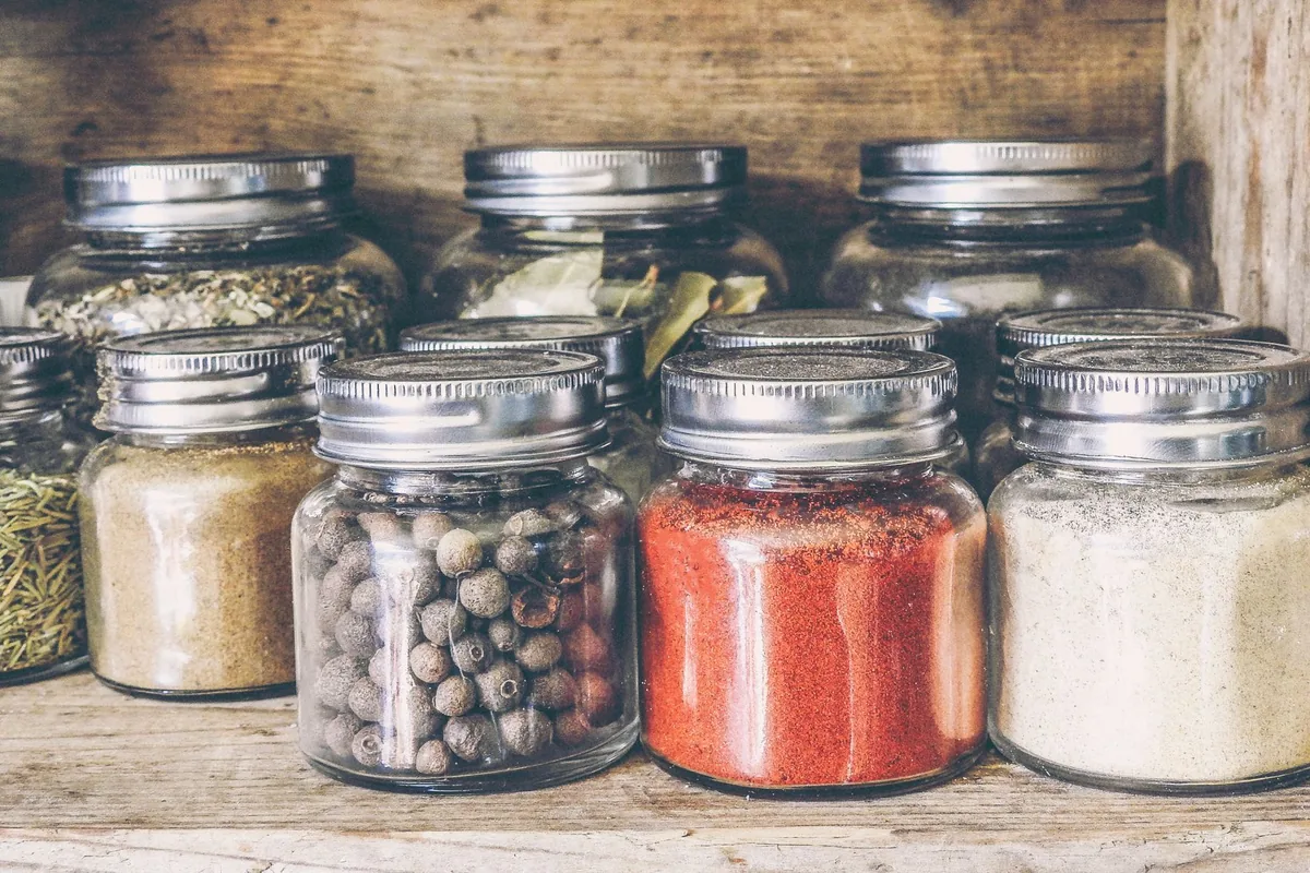 Rows of glass jars holding whole spices on a bright kitchen shelf