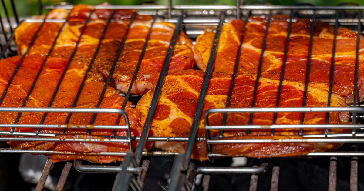 Rows of meat cooking on a large outdoor grill rack