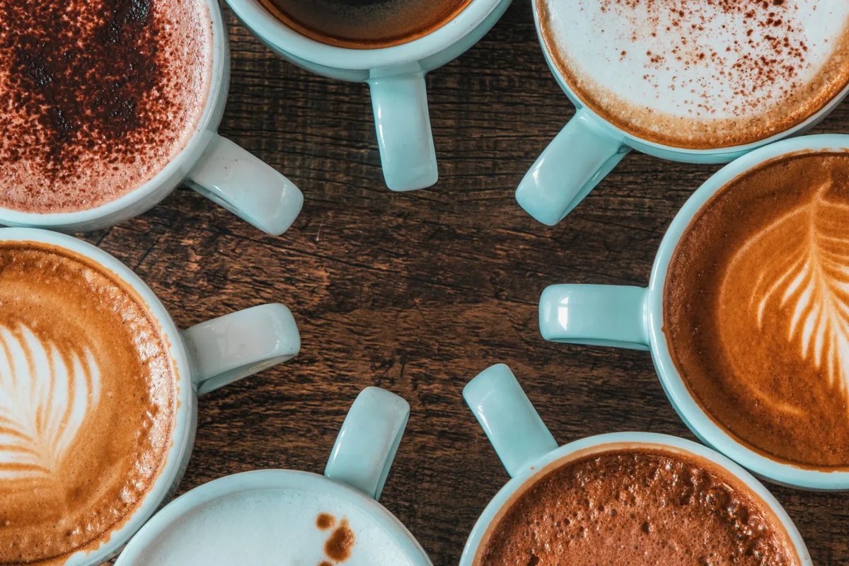 Rows of milky coffees in light blue cups seen from above