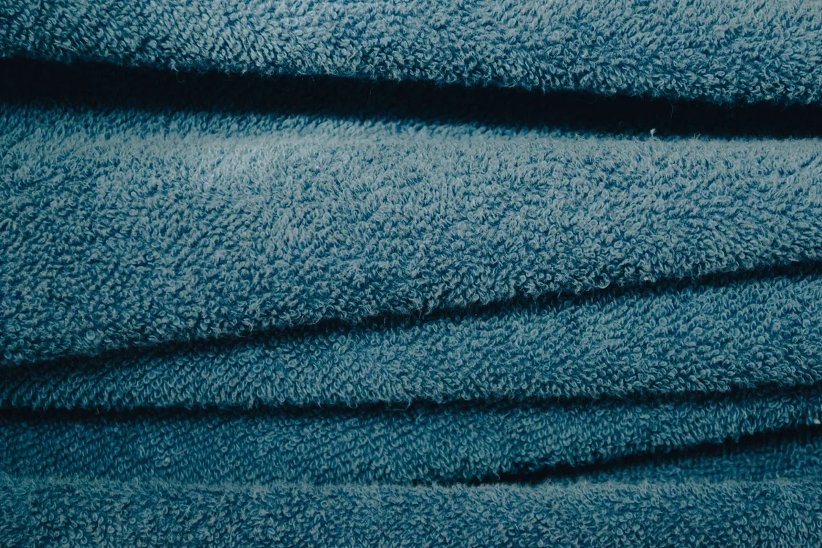 Several folded cotton towels stacked in a pile against a light background