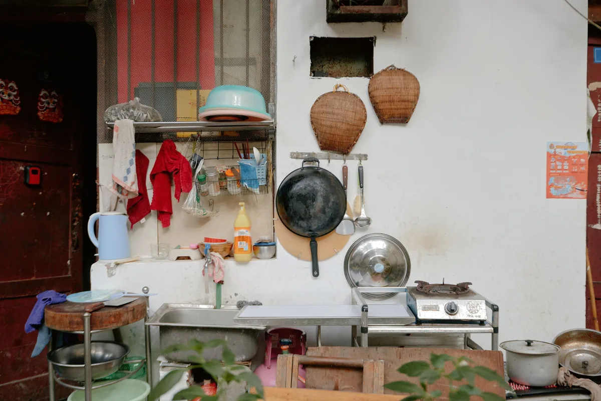 Several frying pans hanging from a rail on a light kitchen wall