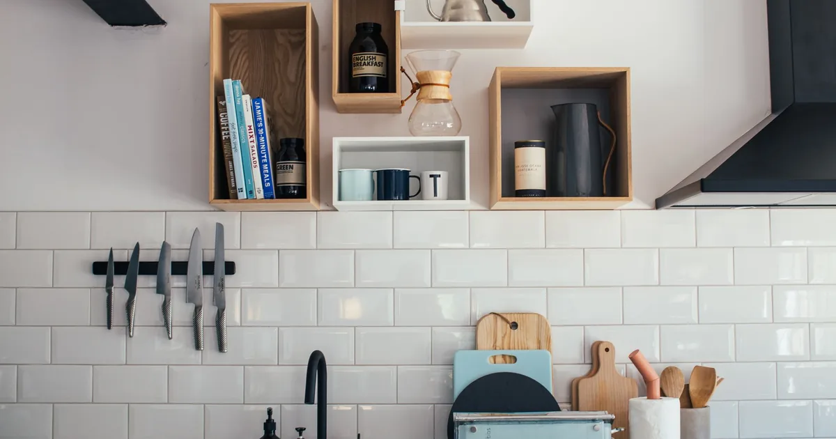 Several kitchen knives hanging from a wall-mounted magnetic strip above a bright kitchen countertop