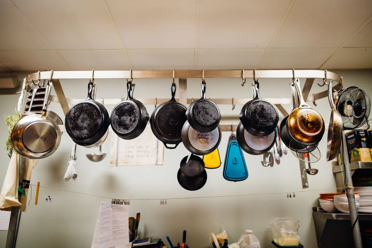 Pots and pans hanging from a rail in a bright kitchen