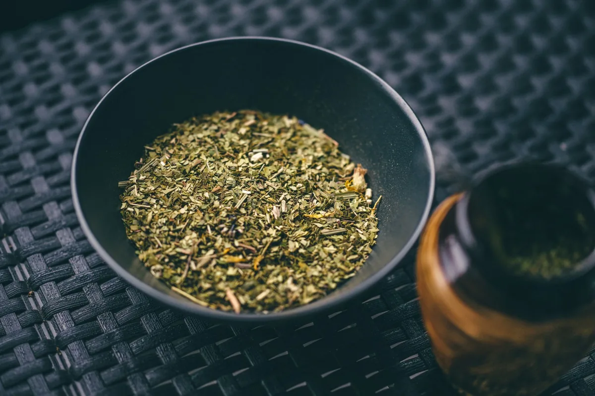 A dark bowl of loose dried tea leaves