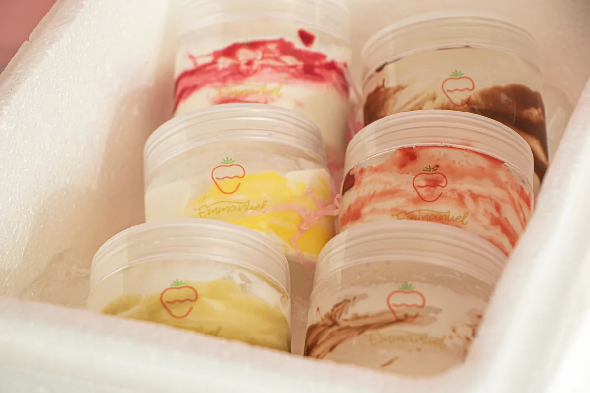 Several tubs of ice cream standing upright on a frosty freezer shelf