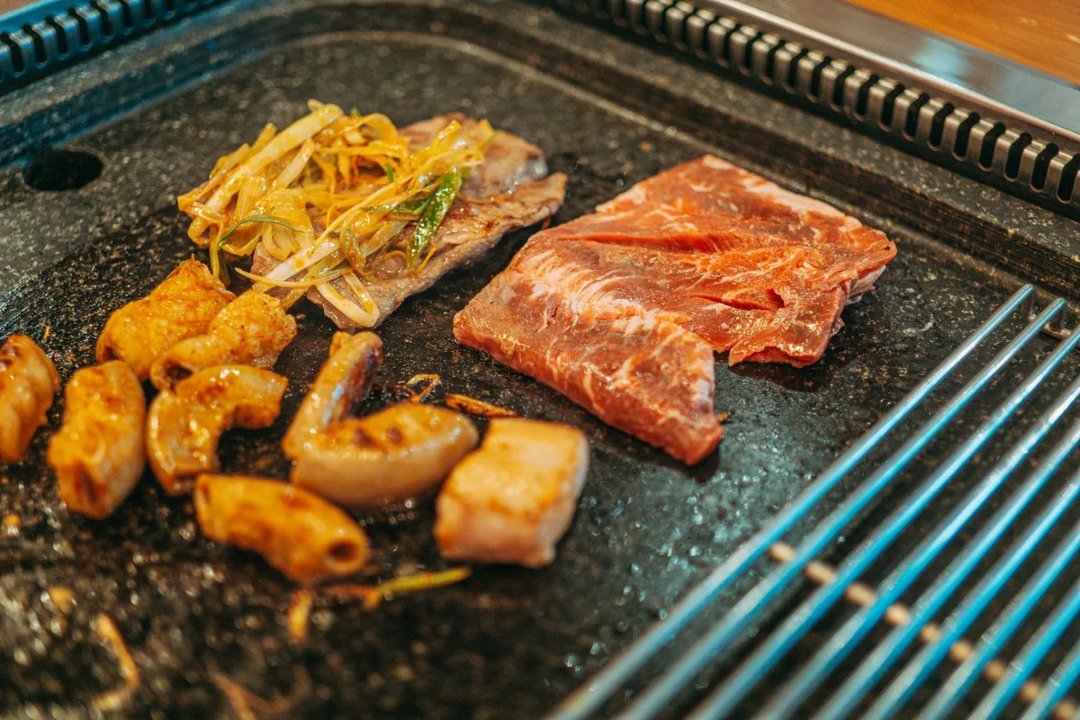 Shrimp, meat and vegetables cooking on a flat griddle plate
