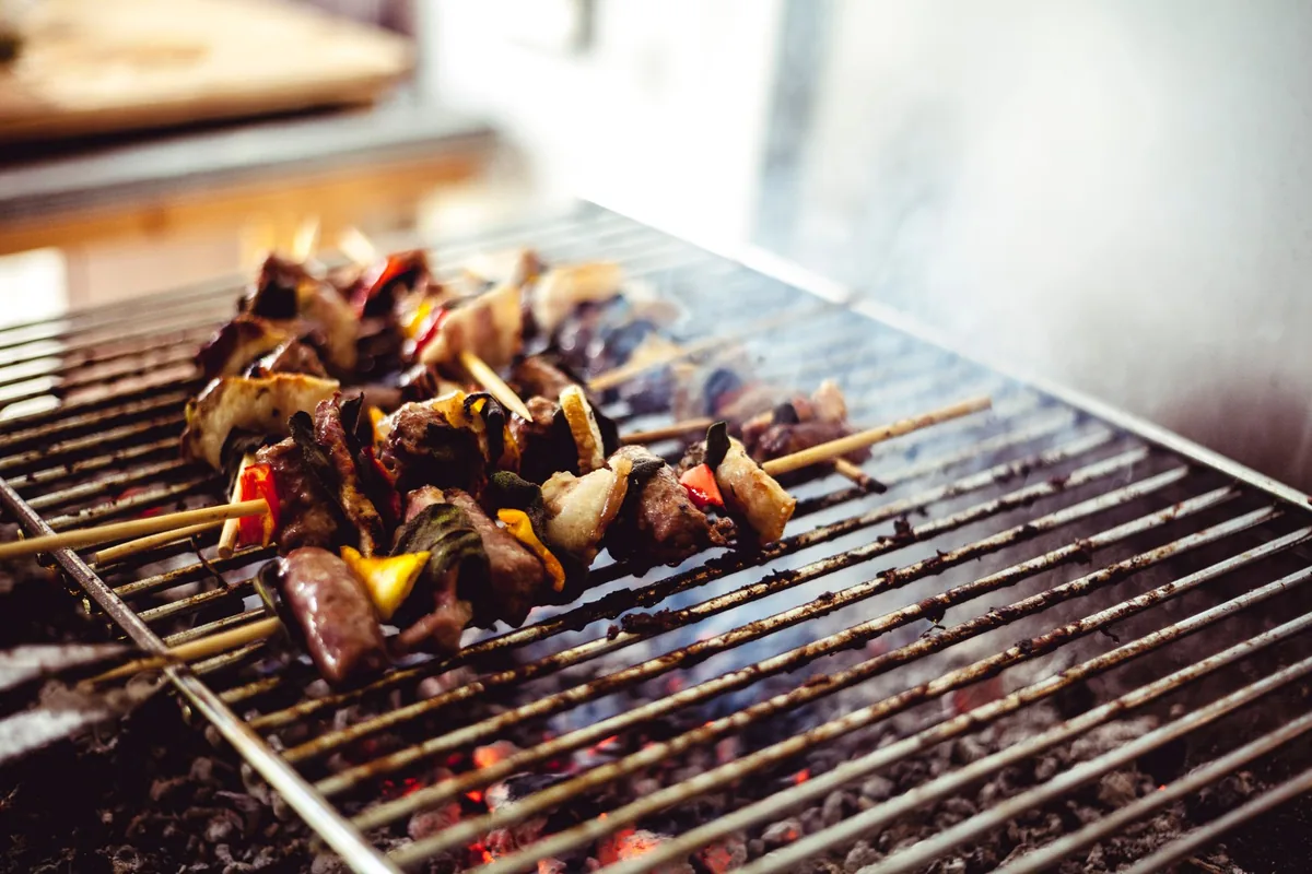 Skewers of meat and vegetables cooking on a grill grate