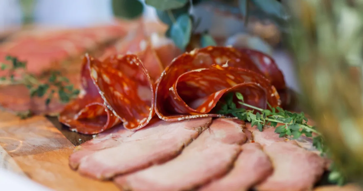 Sliced cured meats on a wooden board