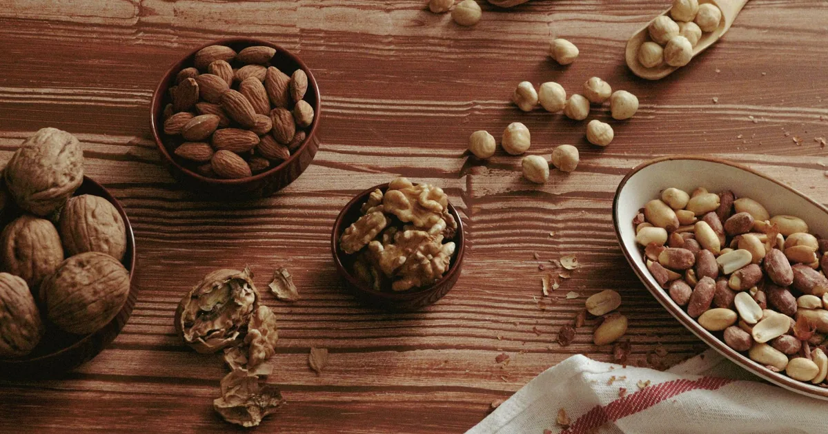 Small bowls of almonds, walnuts and hazelnuts on a light wooden kitchen counter
