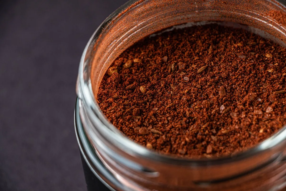 Small glass jars of red, yellow and brown ground spices lined up in a row