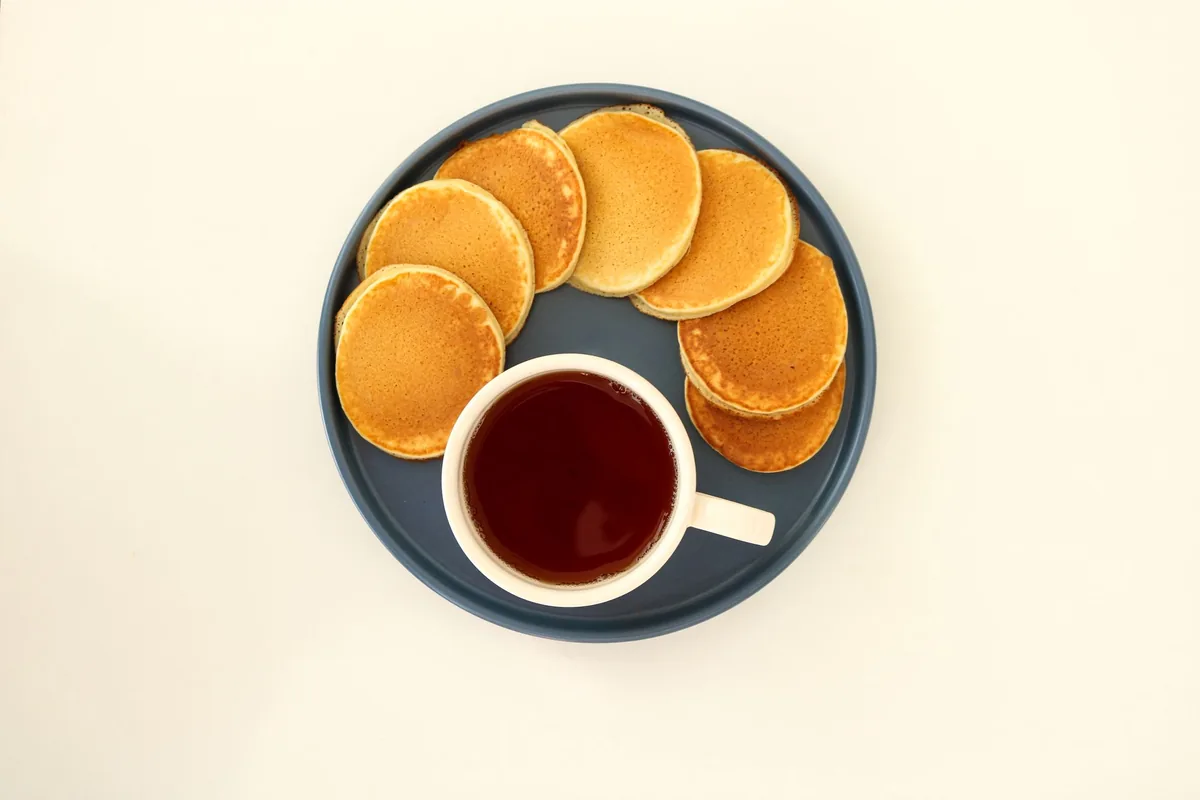 Small pancakes arranged around a cup of tea