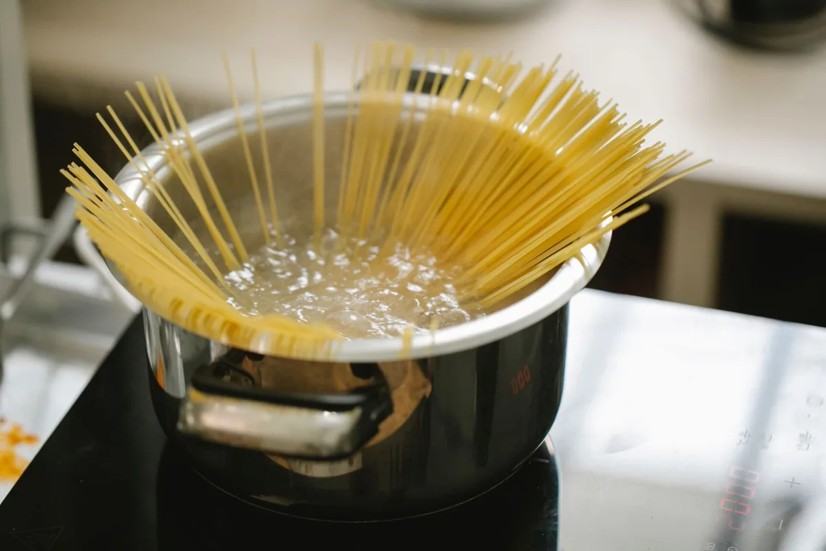Spaghetti boiling in a large pot of water on a hob