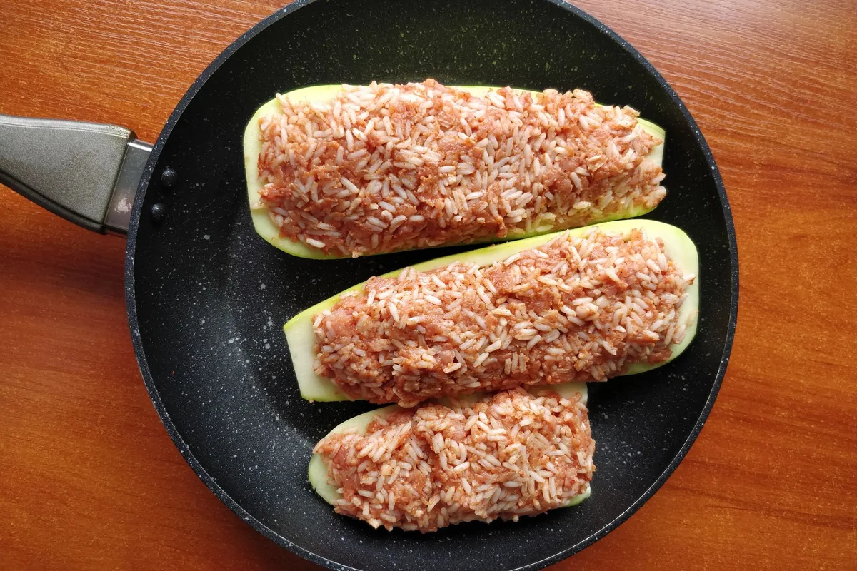Stuffed zucchini halves in a dark nonstick pan