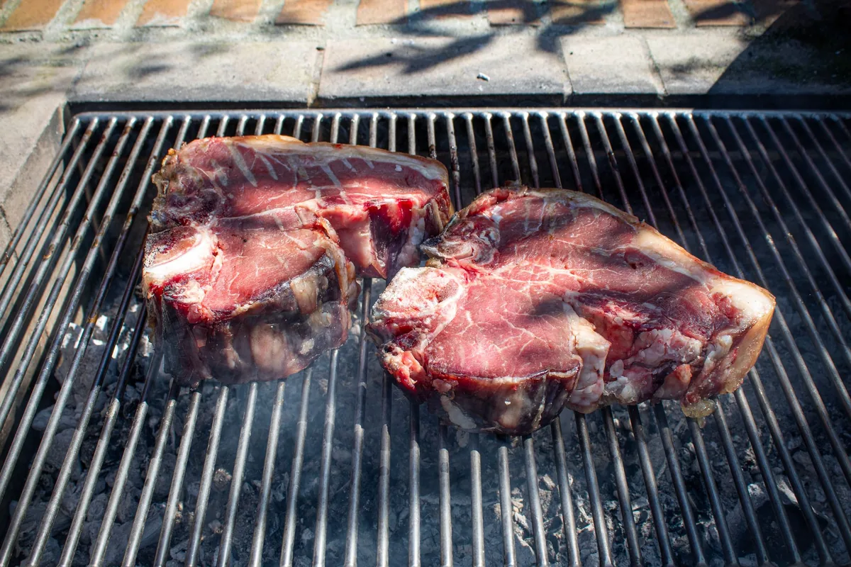 Thick steaks searing on a grill grate