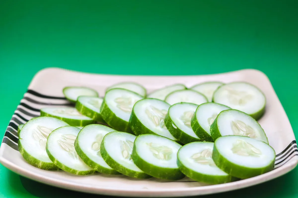 Thin, even cucumber rounds fanned out across a white plate