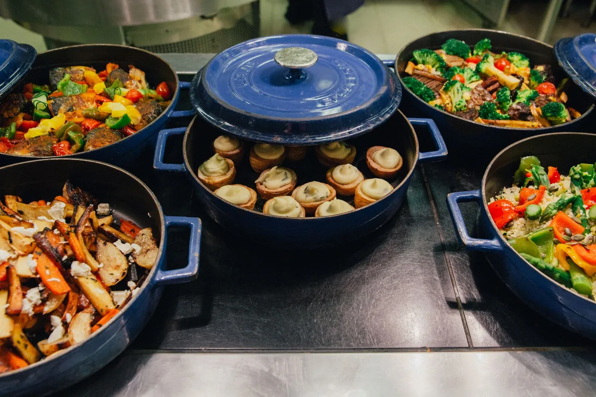 Three pans cooking at once on the burners of a clean stovetop