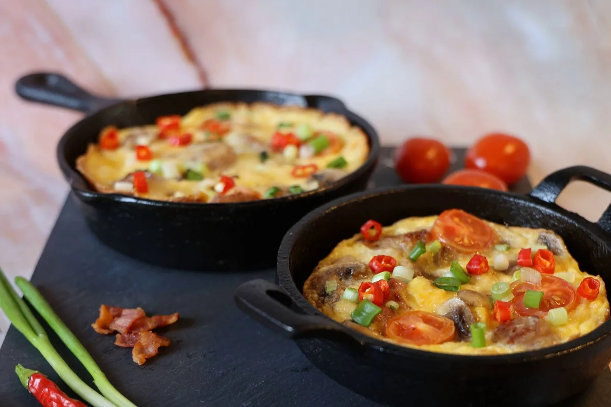 Two vegetable frittatas in cast iron skillets