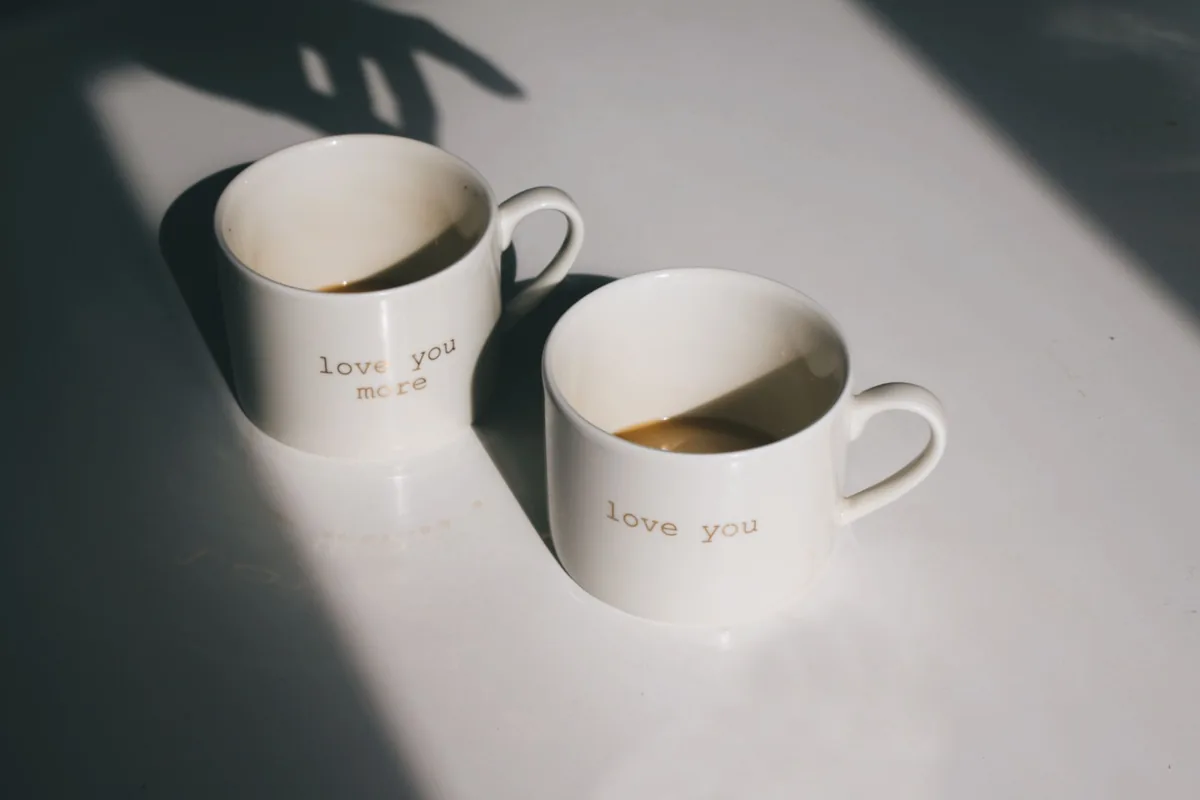 Two white mugs on a sunlit table
