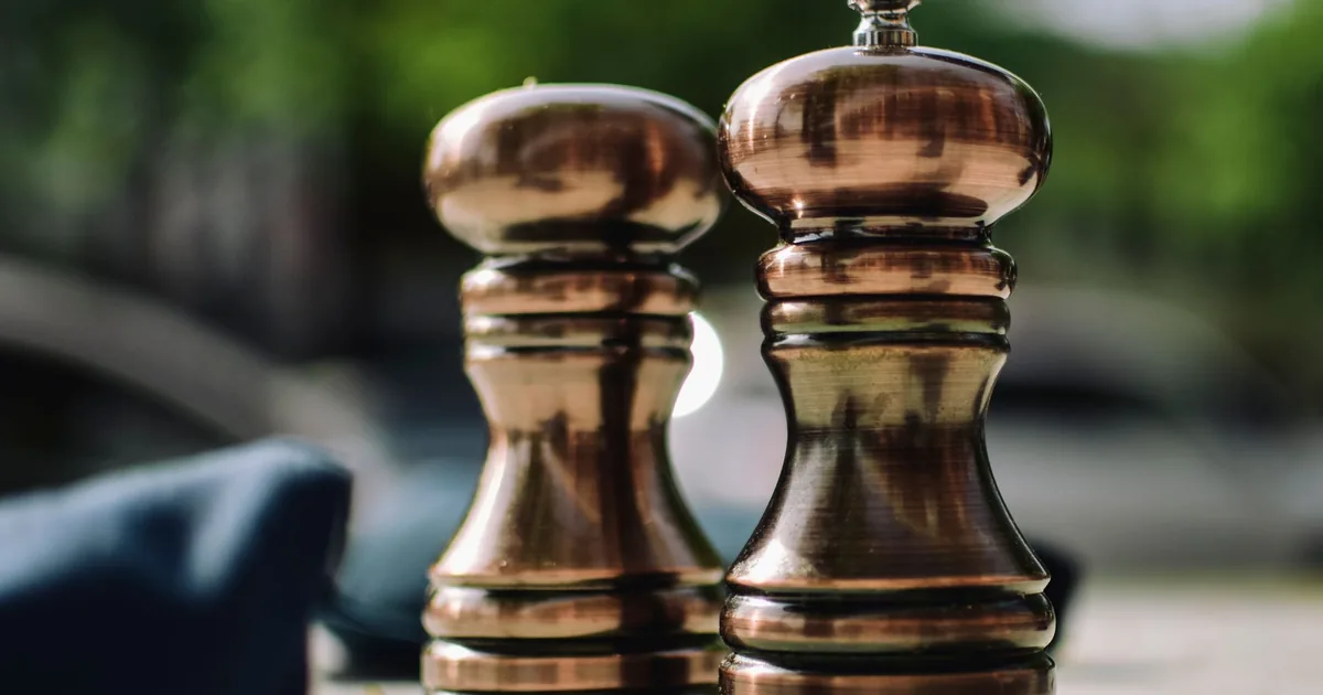 Two wooden-topped pepper mills standing side by side