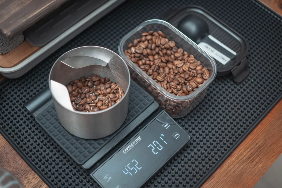 Whole coffee beans being weighed on a small digital scale